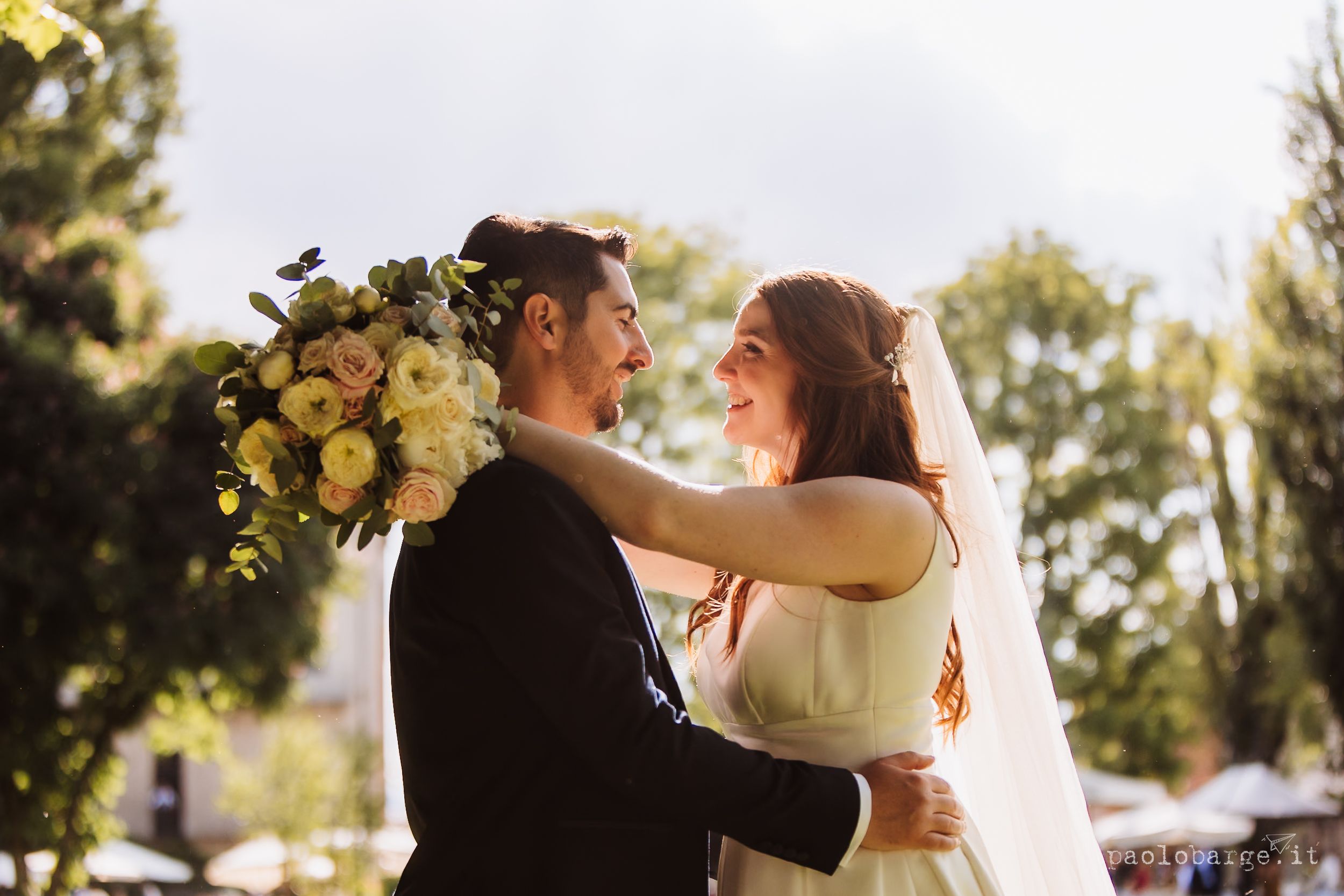 A couple shares romantic moments outdoors during their sunset wedding celebration against a natural backdrop.