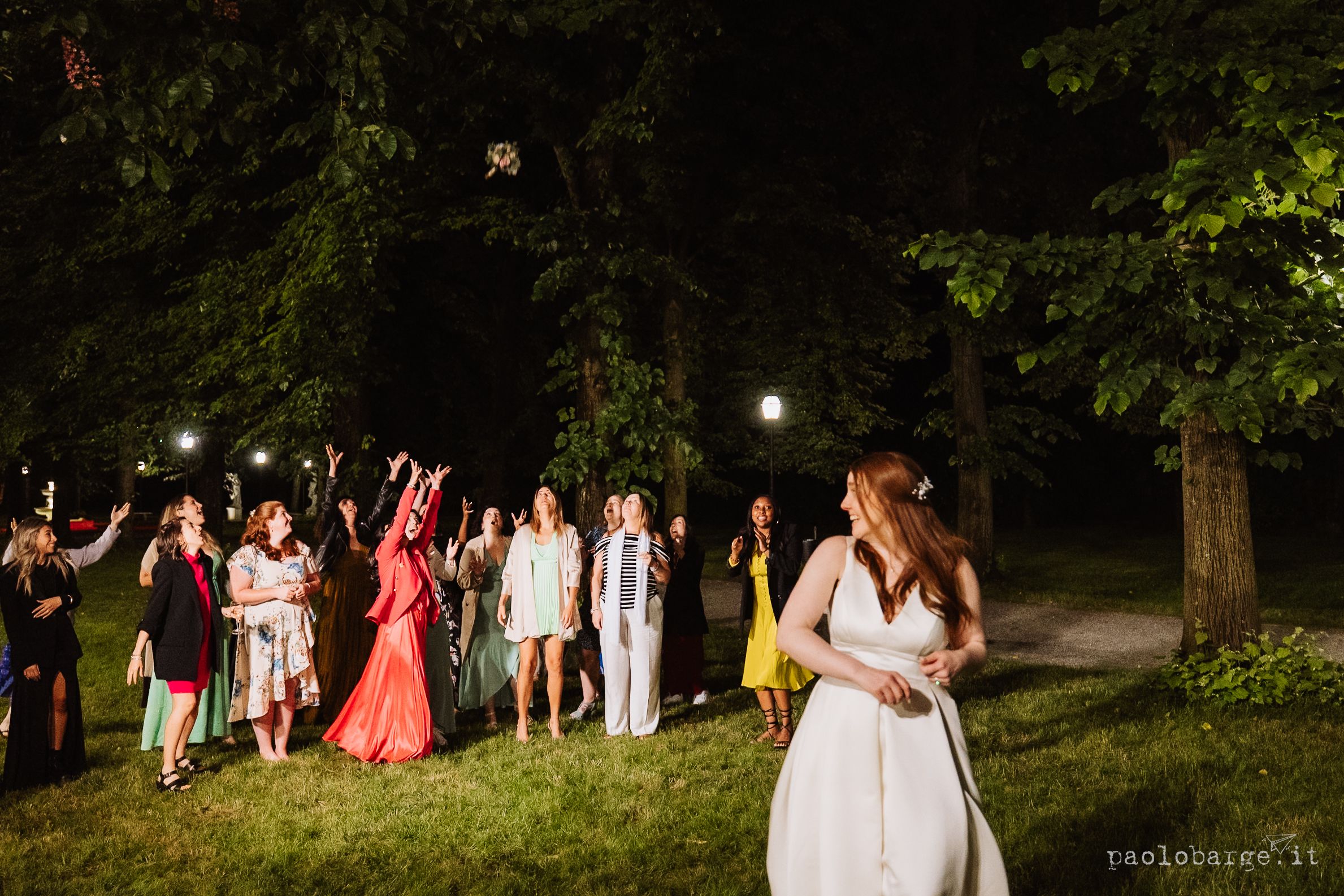 A nighttime outdoor celebration scene with glowing lights and people joyfully gathering in a garden setting.