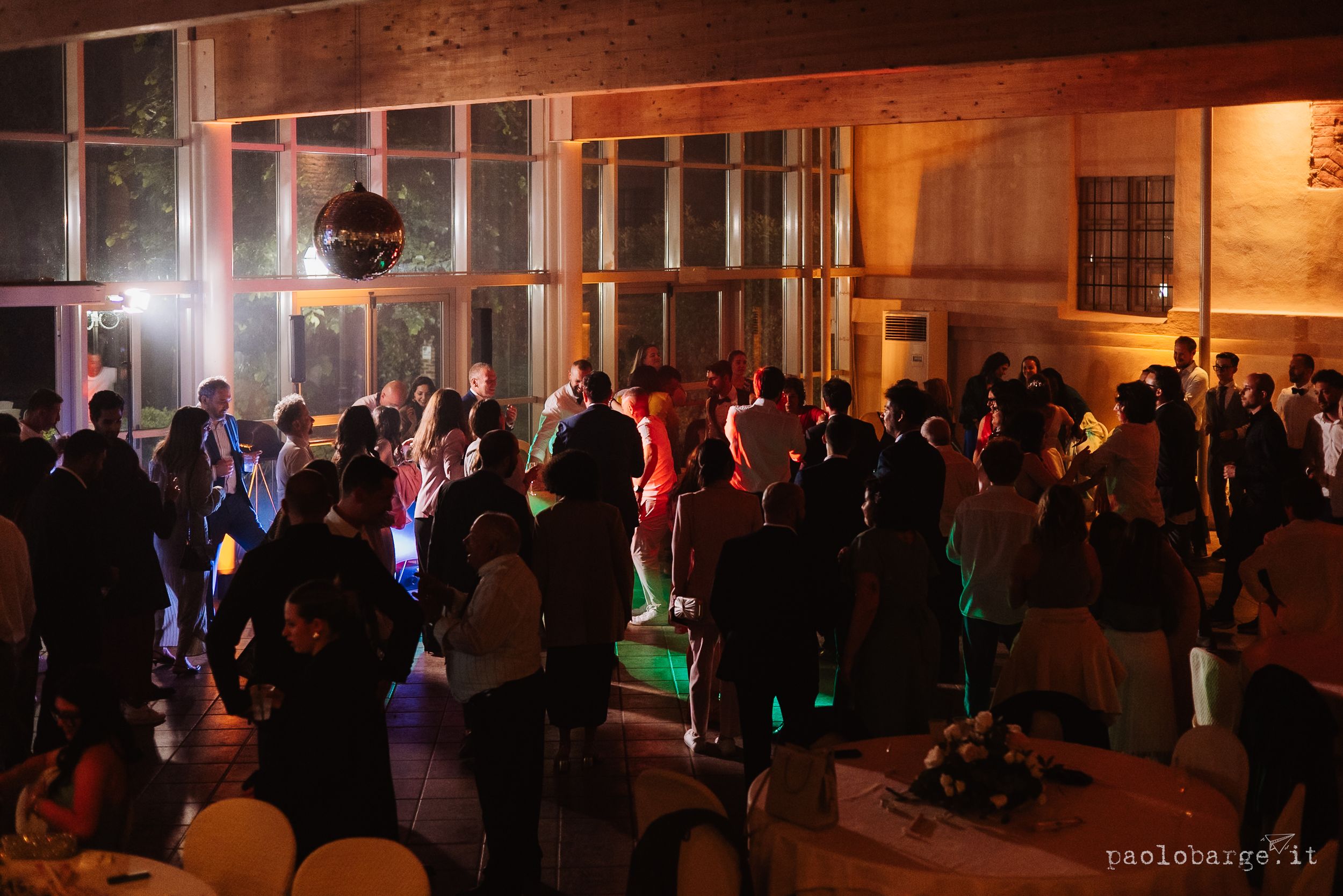A crowded nighttime dance party on a street with disco lights and glowing ambiance against building facades.