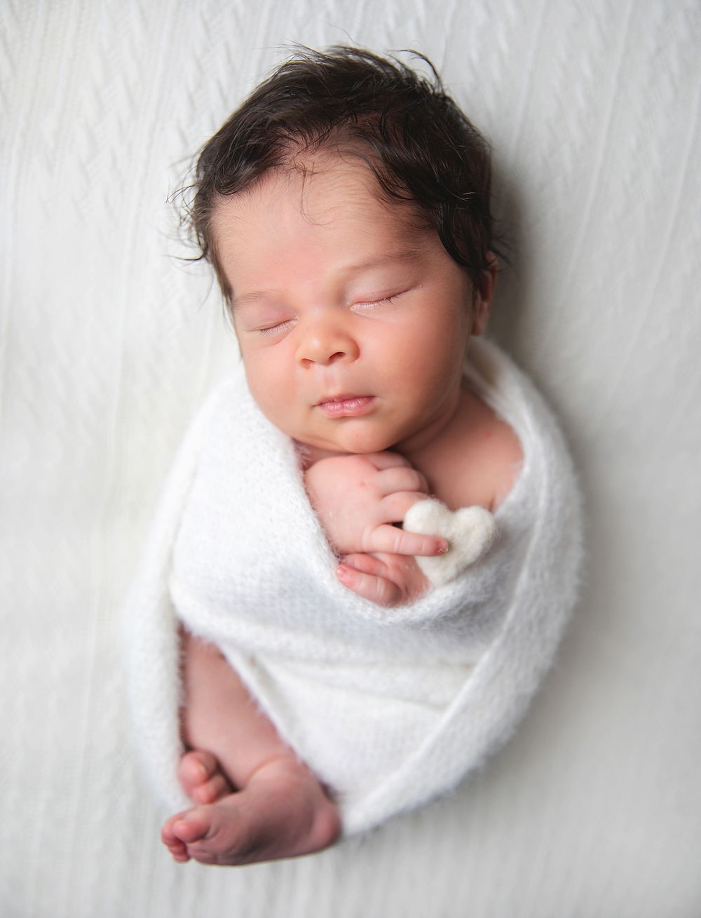 Newborn baby swaddled in white blanket sleeping peacefully against light background in collage of poses. During a newborn session in London
