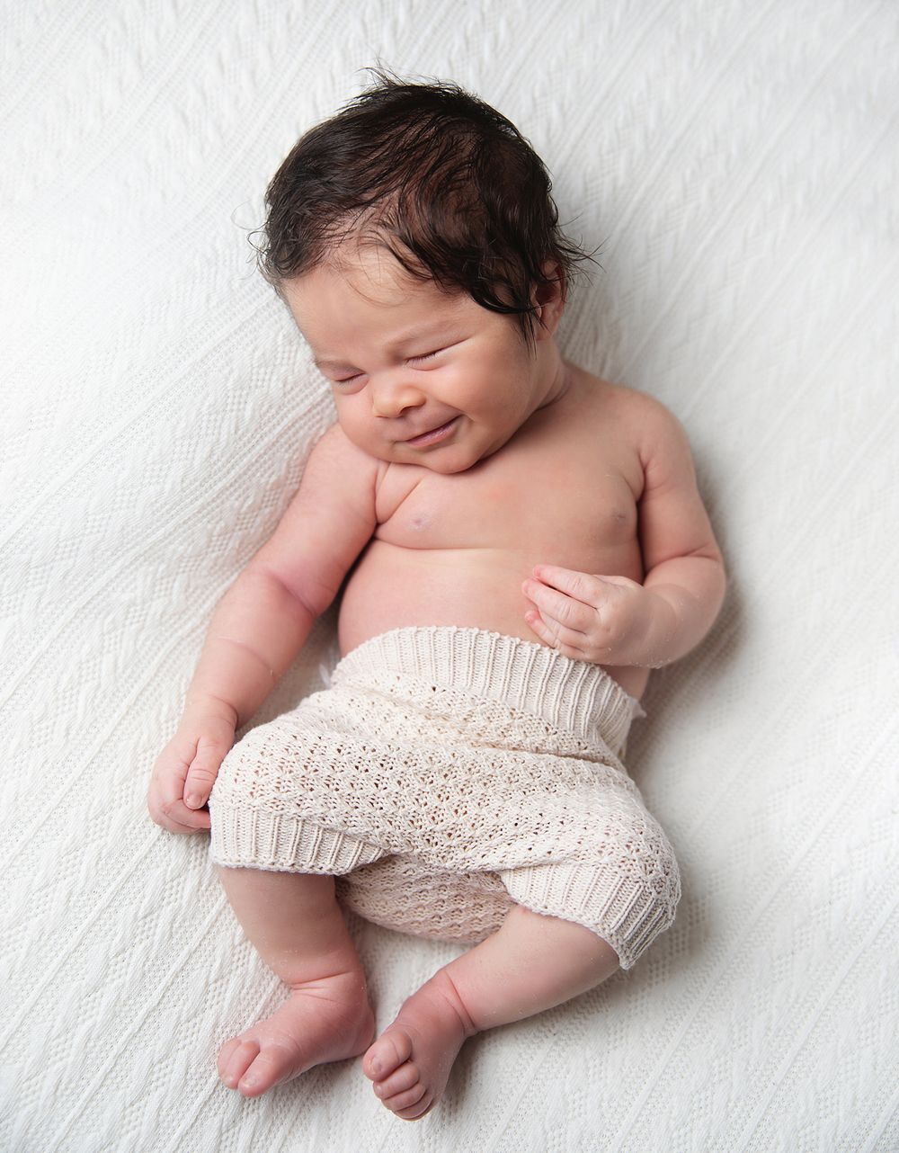 Four peaceful sleeping newborn baby photos in portfolio style layout against white background, partially covered in beige knit wrap.