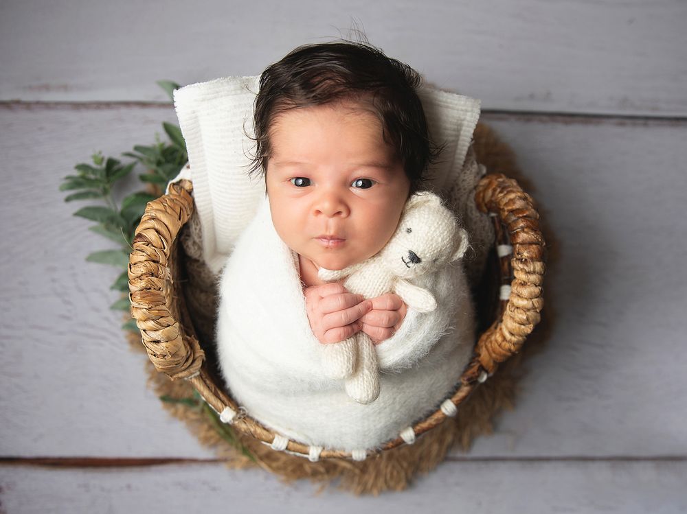 A five-image collage shows a baby lying down on white fabric with straw-like decorative elements around their head. During a newborn session