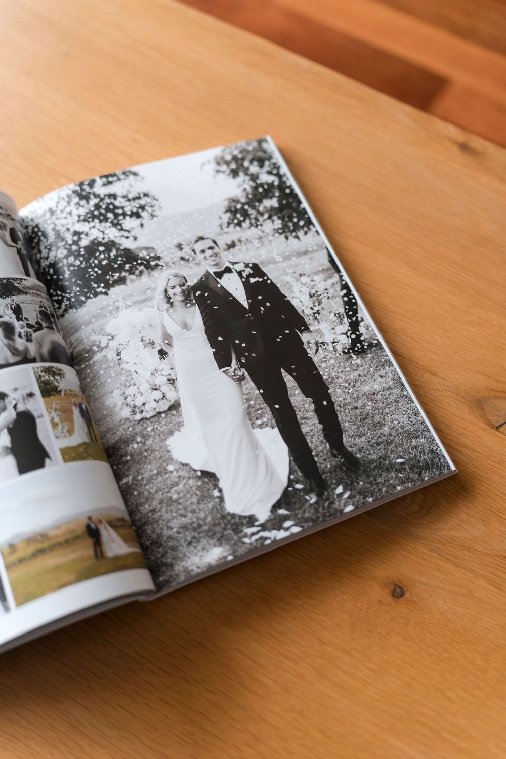 An open photography book on a wooden table displays black and white vintage photographs across its pages.