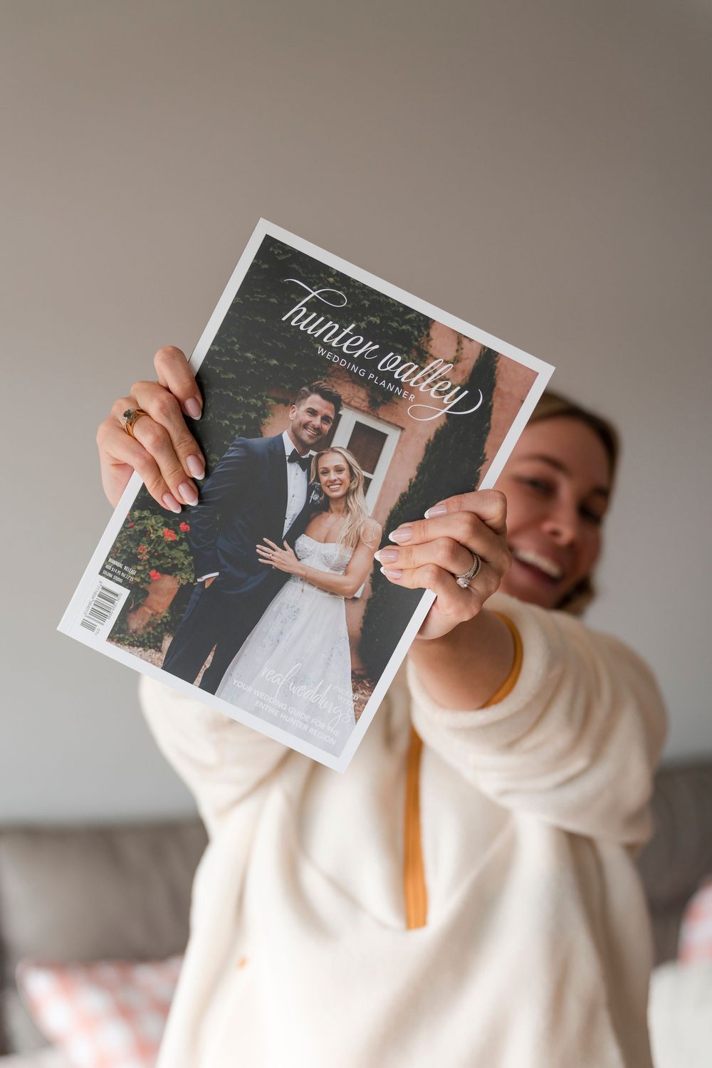 Someone holding up a wedding photo album while wearing a cream-colored sweater.