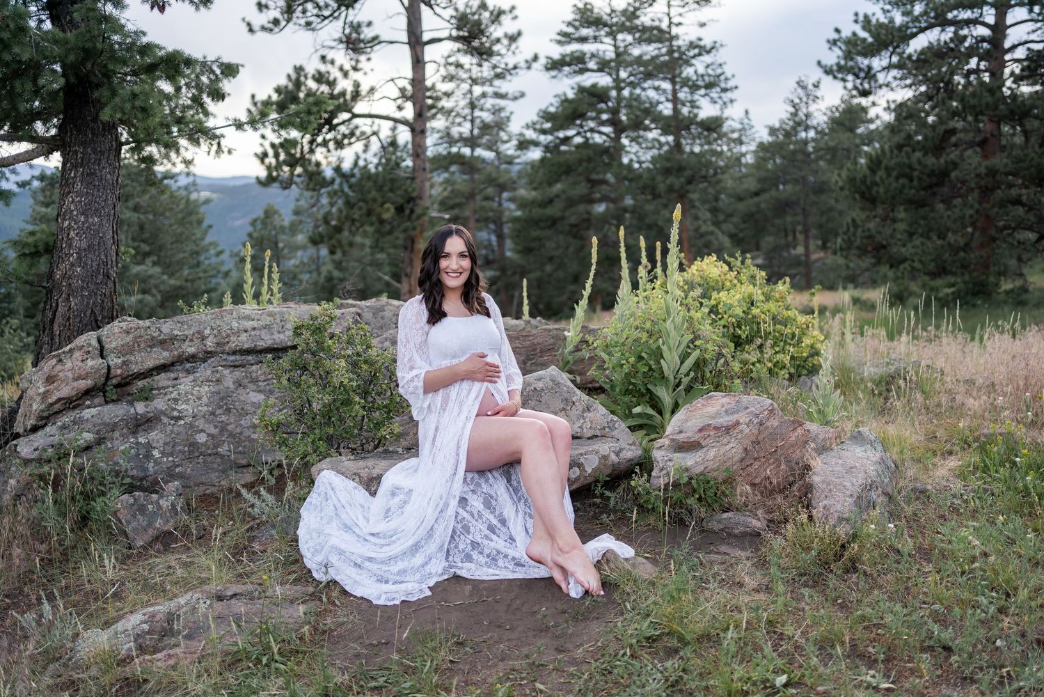 A collection of outdoor portrait photos featuring a person in a white dress sitting among pine trees and rocky terrain.