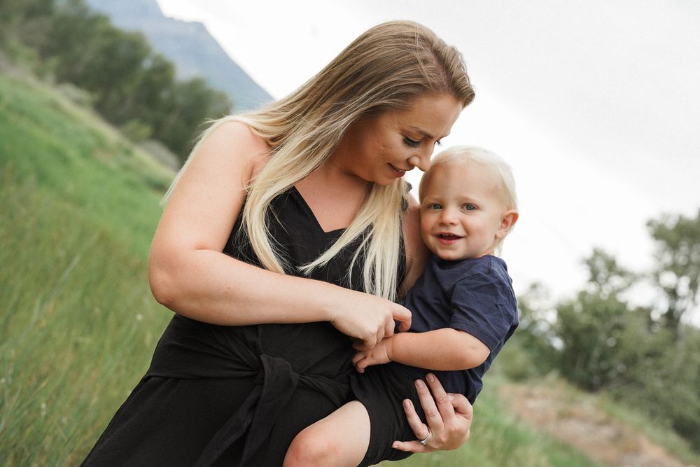 Parent and child share intimate moments in a series of outdoor photos with green mountain landscapes in the background.