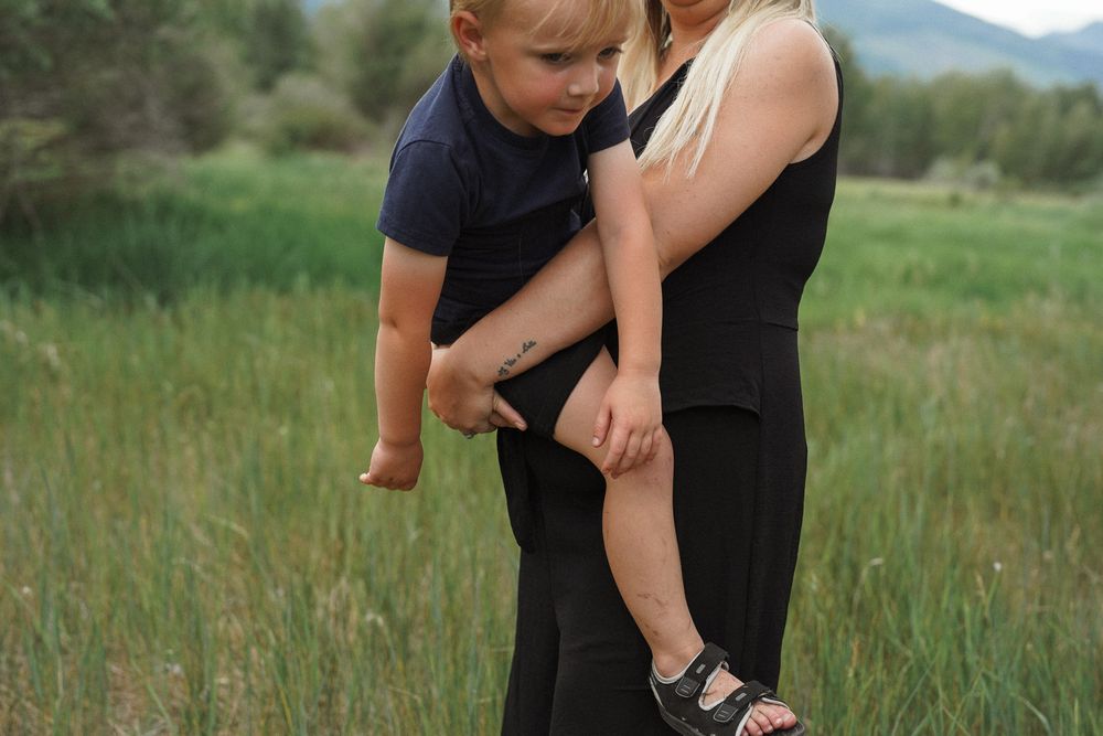 A series of candid outdoor family portraits taken in a green meadow with mountains in the background.