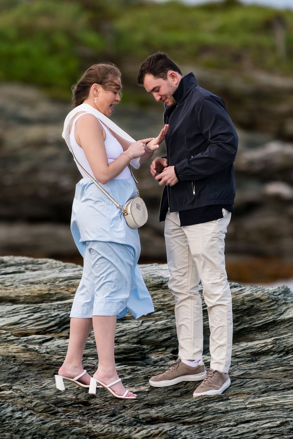 A romantic moment captured on rocky coastal terrain with dramatic natural lighting.