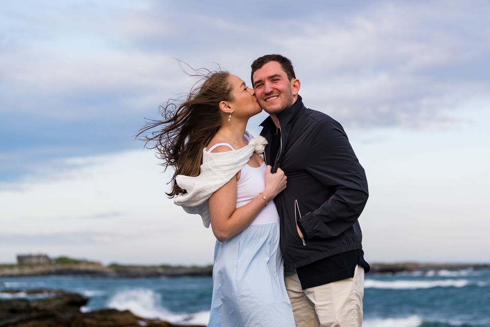 Windy oceanside photo session with waves crashing against rocky Maine coast.