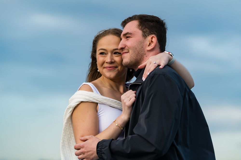 A couple shares an intimate moment against a blue sky backdrop.