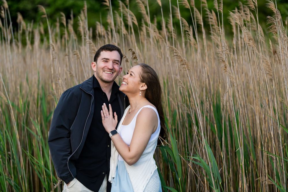 A tender embrace photographed among tall swaying reeds in a natural setting.