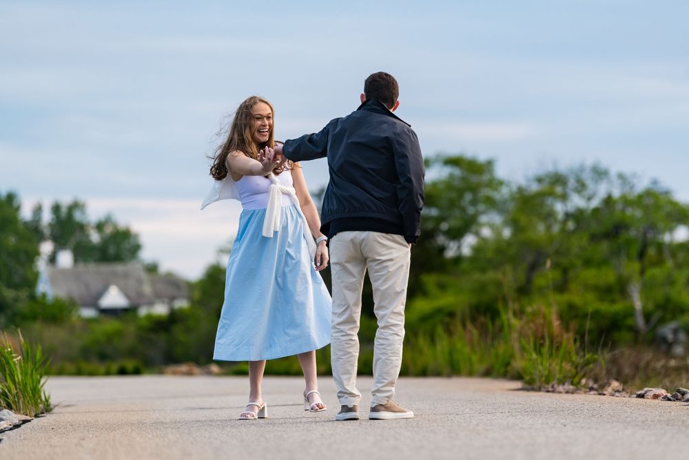 A couple dancing together on a coastal path surrounded by summer greenery and blue skies.