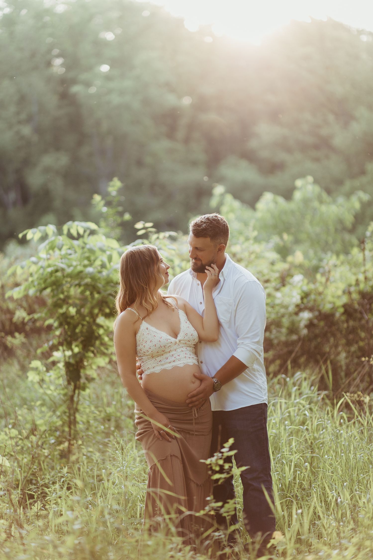 maternity photos in pittsburgh pennsylvania by ash coniglio photography, man and woman pose in a green field, his hand on her belly