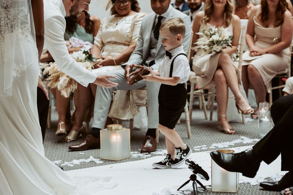 A serene candlelit wedding ceremony in an elegant indoor venue with guests seated in white chairs.
