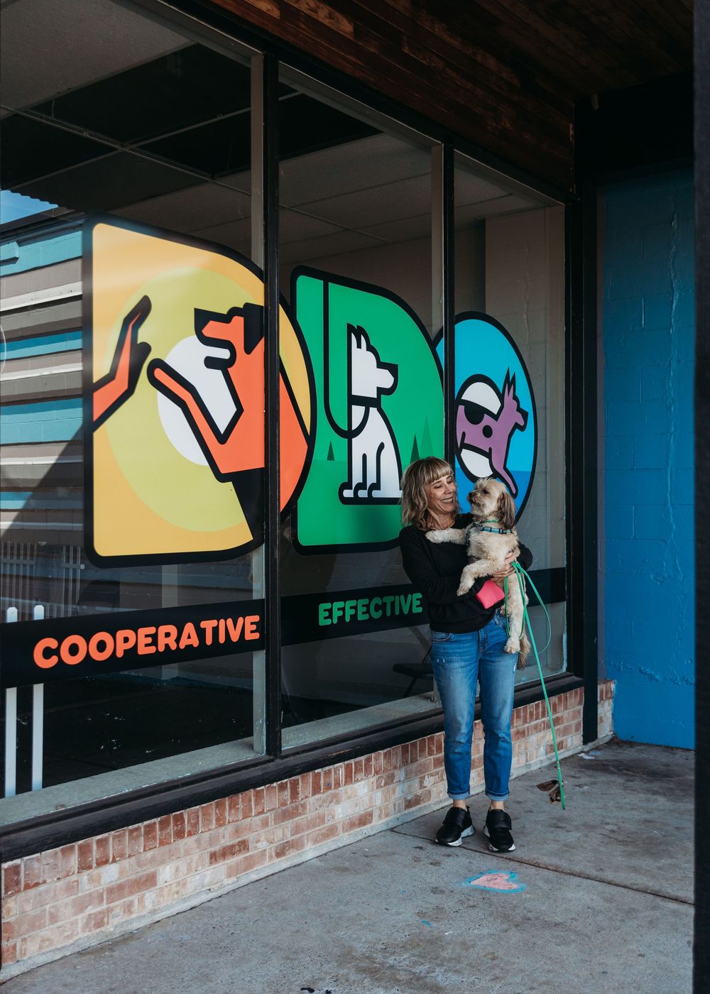 A wall mural featuring colorful abstract designs with text 'COOPERATIVE' and 'EFFECTIVE' outside a modern storefront.
