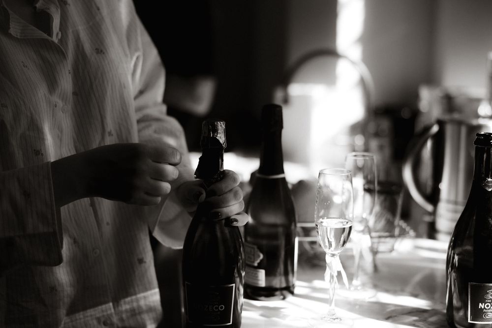 People gathering at a dim bar with bottles and glassware visible in black and white photography.