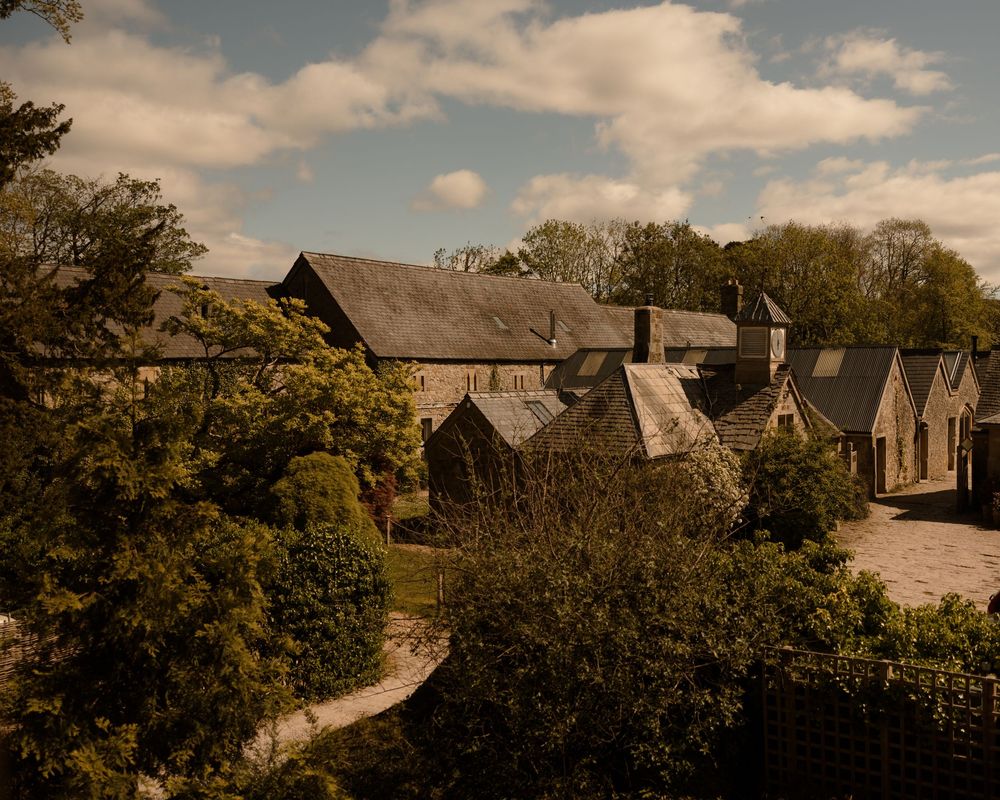 A picturesque stone village with traditional buildings nestled among autumn trees under a cloudy sky.