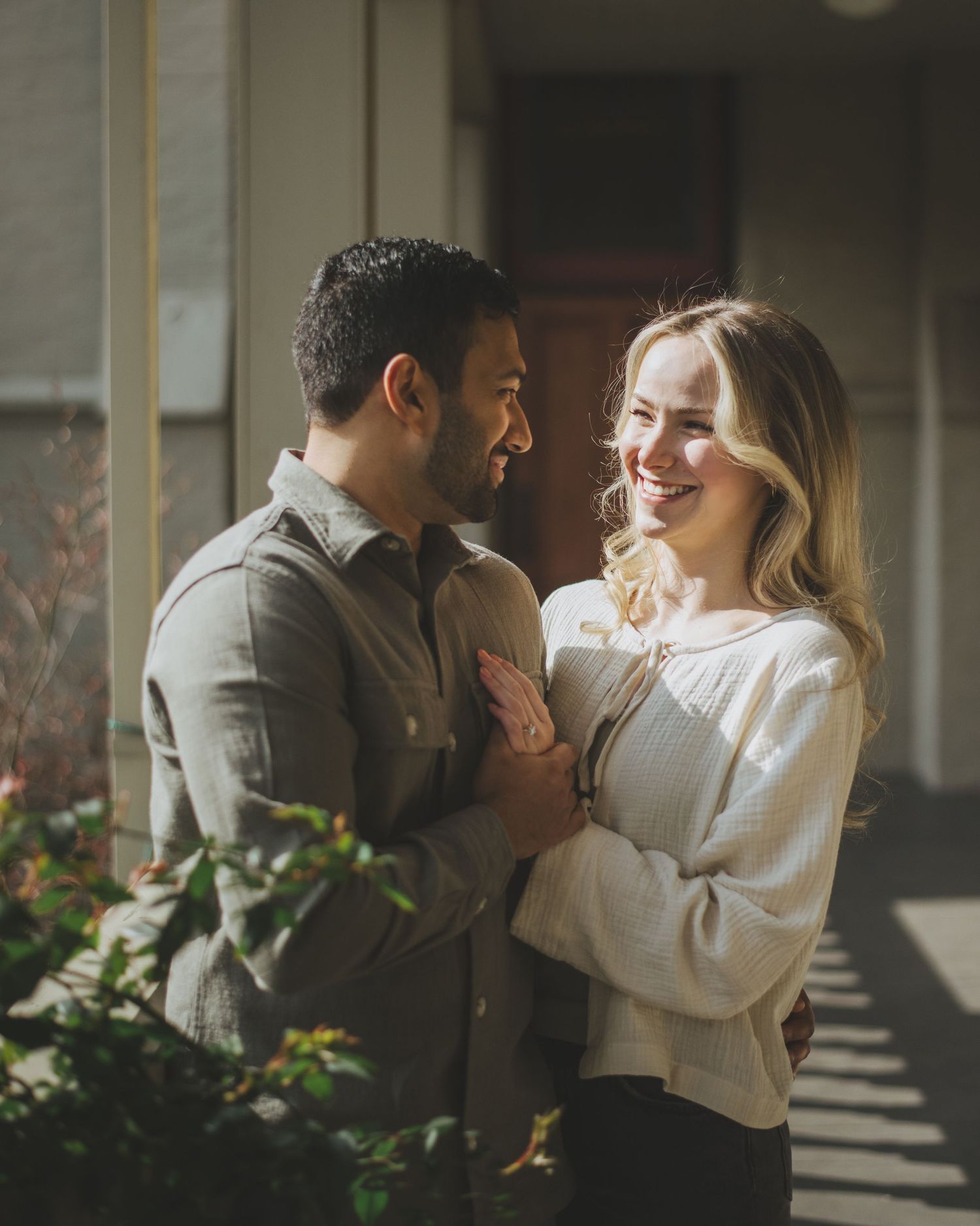 Black and white romantic portrait of a couple dancing outdoors with backlit sunlight creating a dreamy atmosphere.
