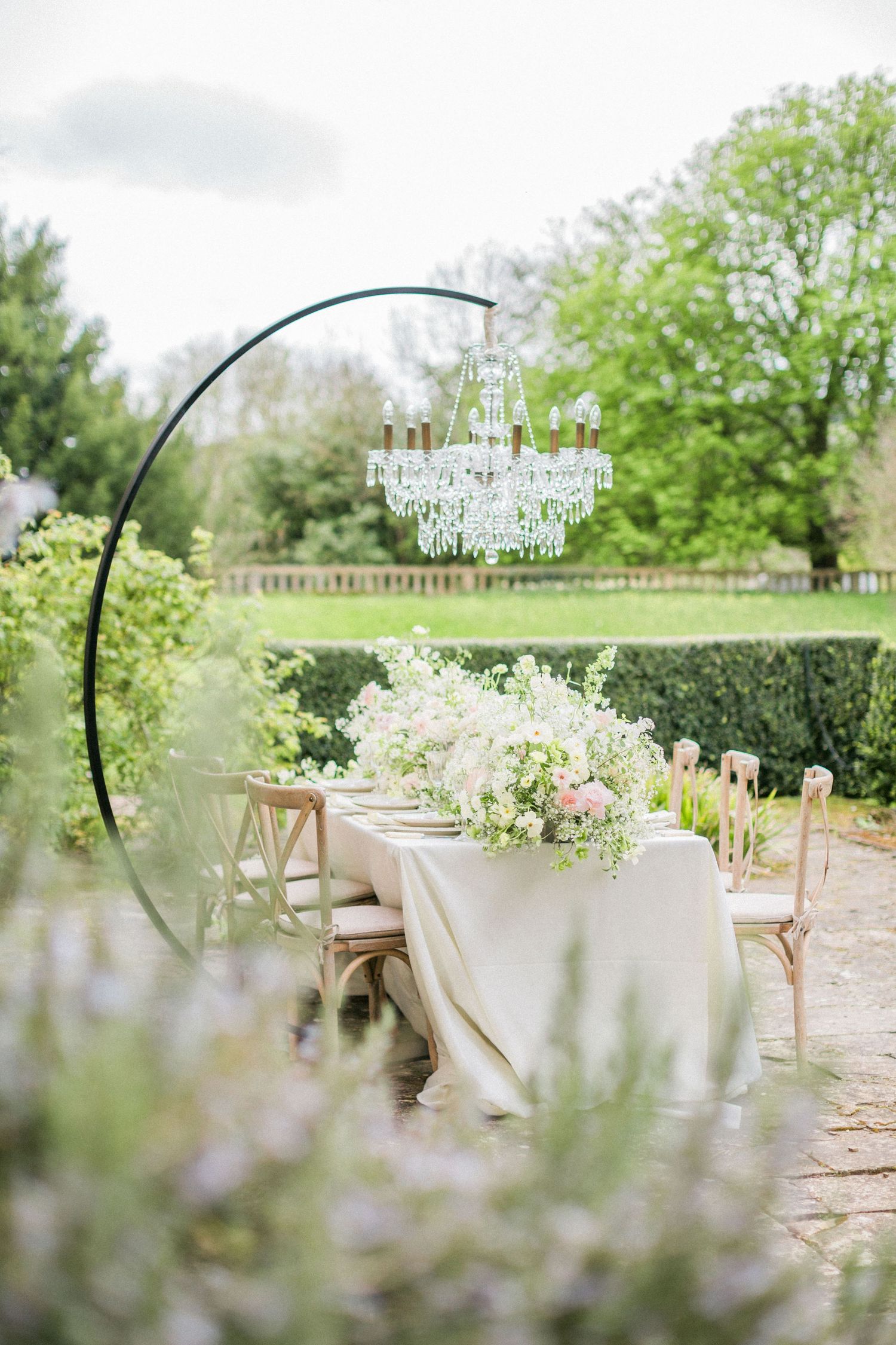 Elegant outdoor wedding setting with crystal chandelier hanging with an abundance of florals Sudeley Castle Hayley Elizabeth Photographer