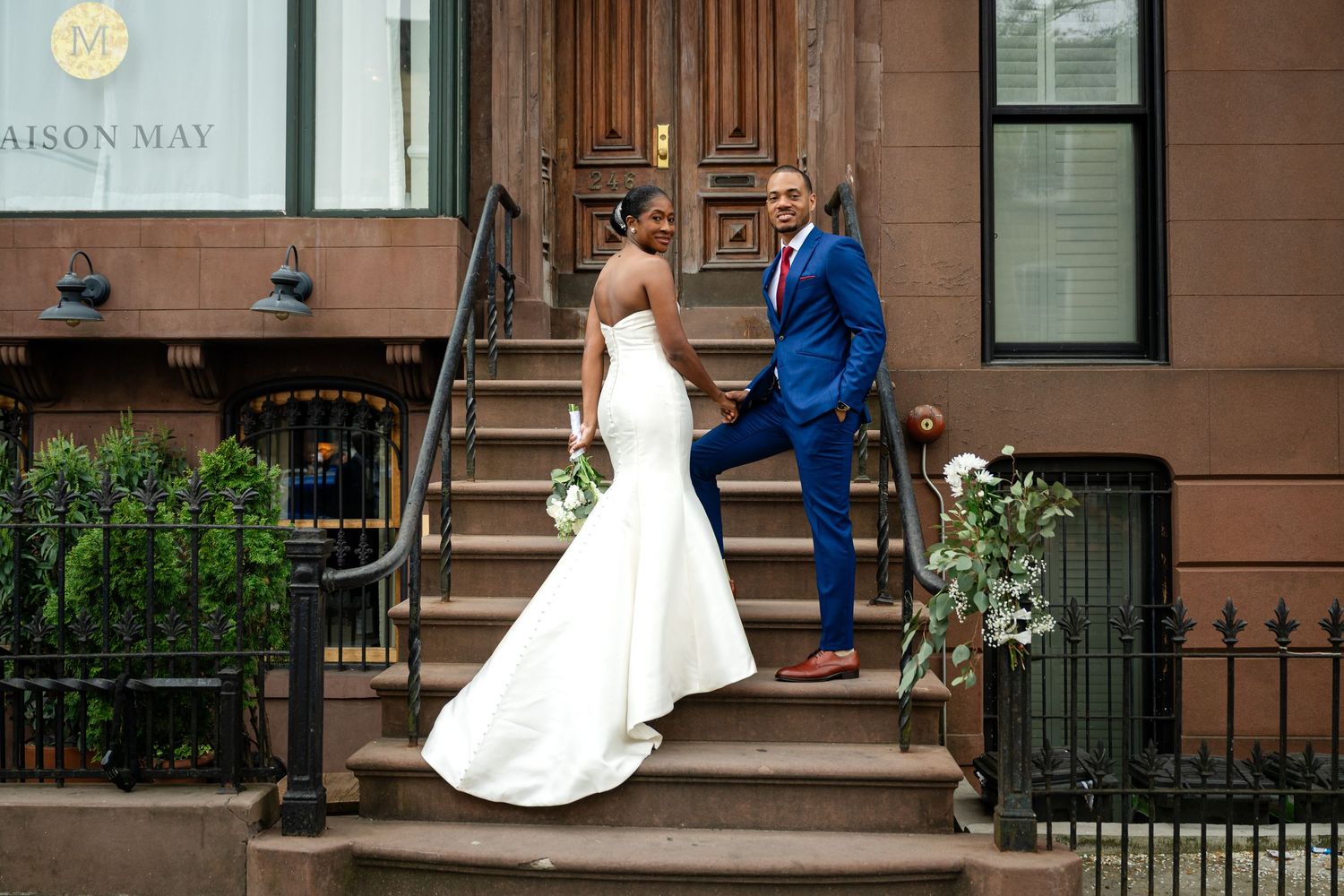 Elegant brownstone entrance with wedding couple posing on historic steps.