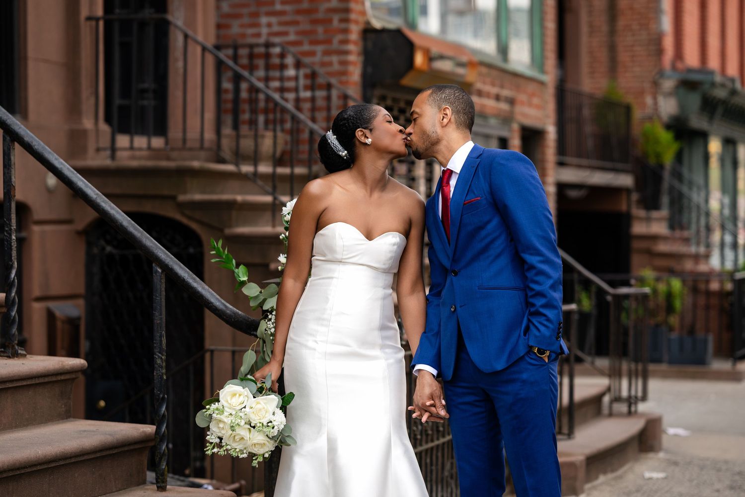 A newlywed couple sharing a tender moment on urban brownstone steps.