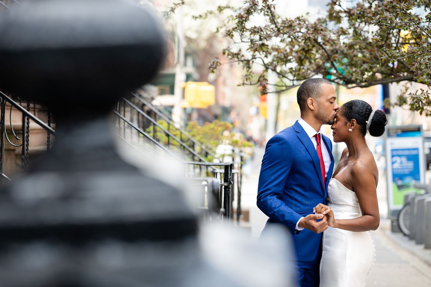 A romantic wedding moment captured on a city street with a bright blue suit and elegant white dress.