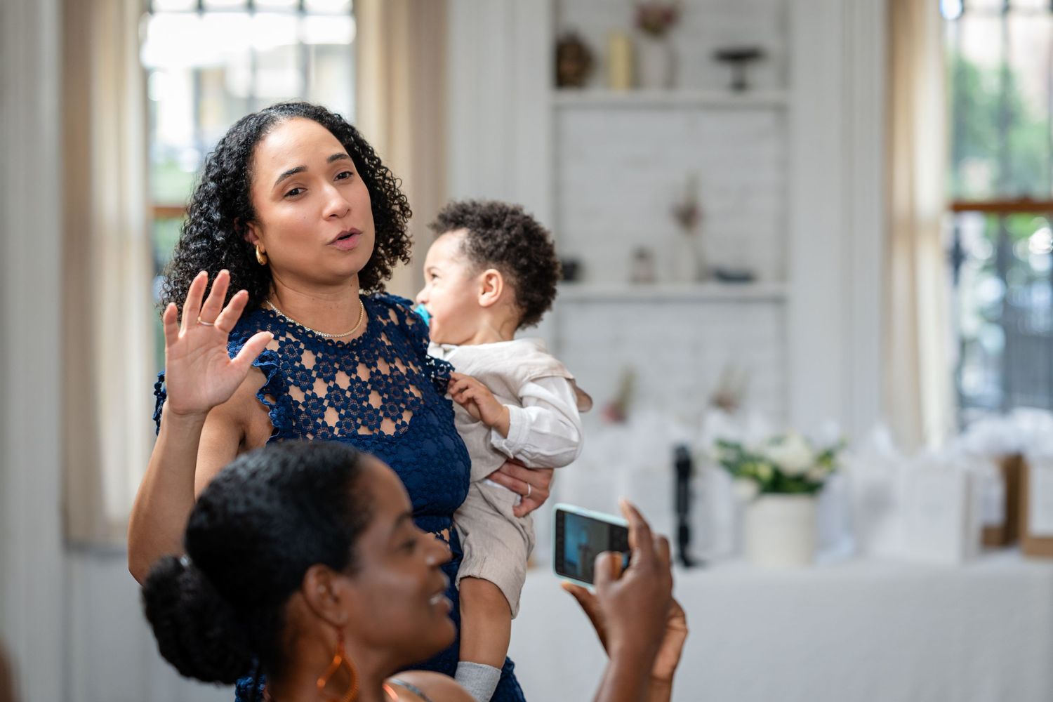 A candid moment at a family gathering with a baby being held up while others take photos.