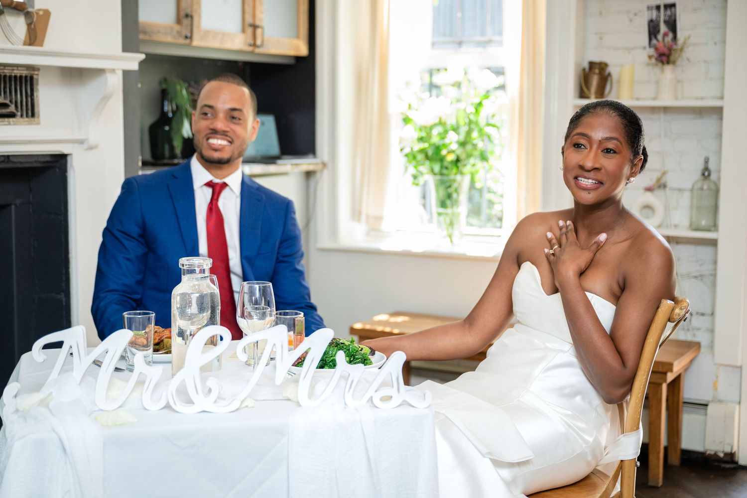 Wedding couple seated at an intimate reception table with decorative settings.