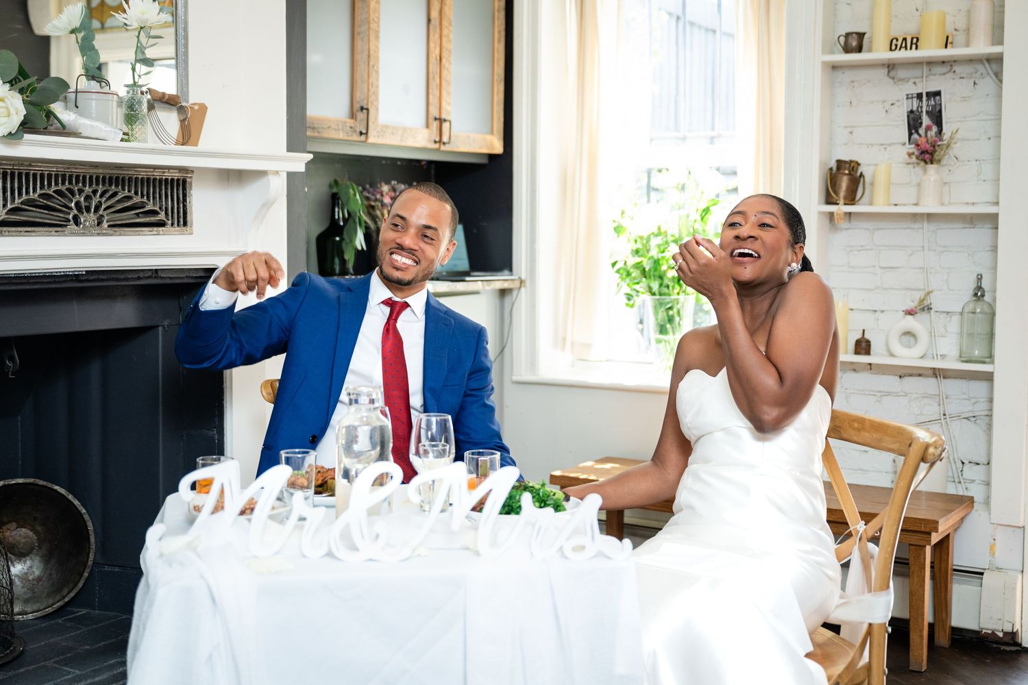 Couple at their wedding reception table sharing a candid moment of laughter together.