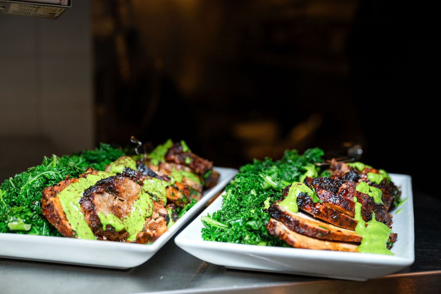 Close-up of plated dishes featuring broccoli and seared protein with garnish.