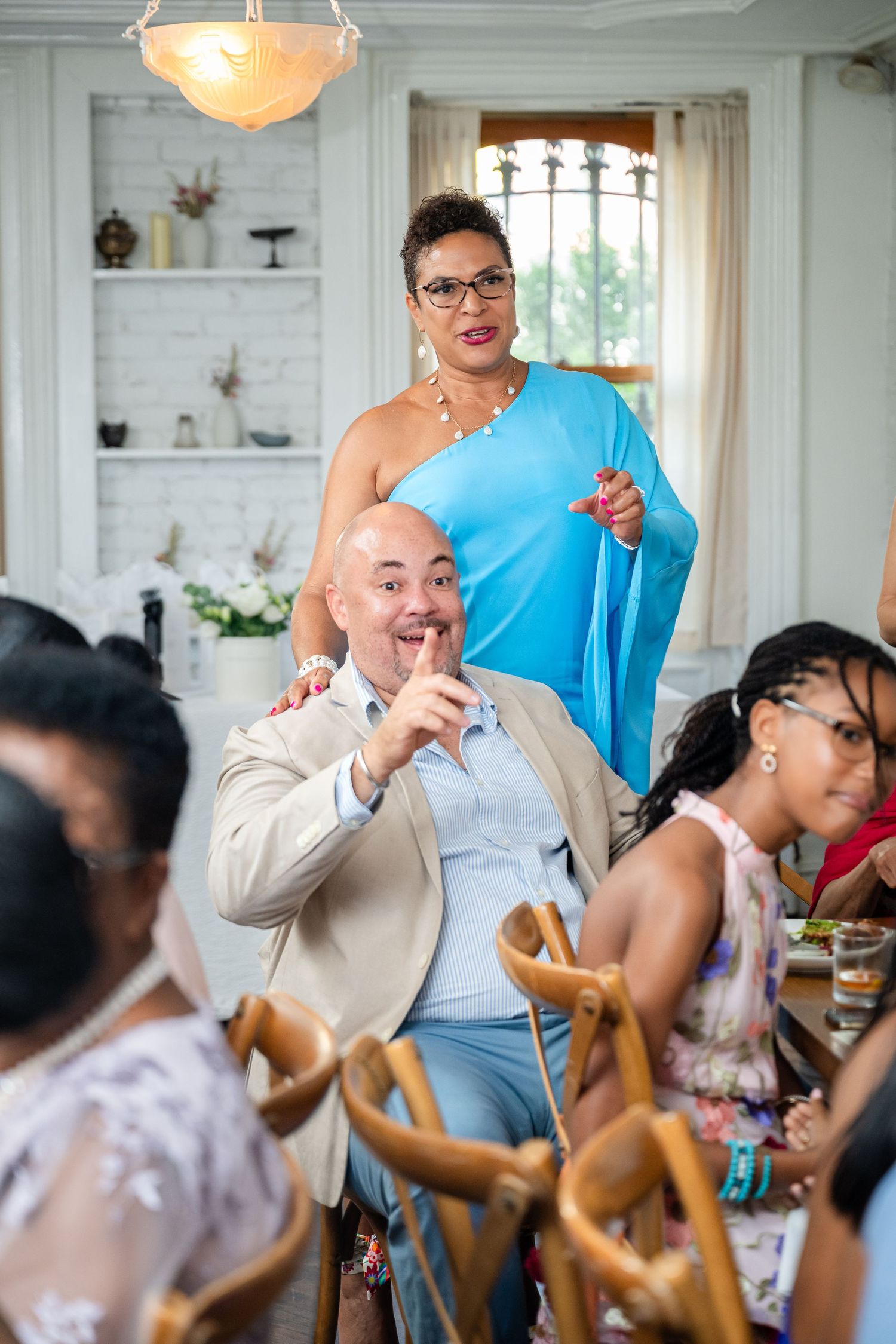 Lively celebration at an indoor dinner party with guests enjoying themselves under an ornate chandelier.
