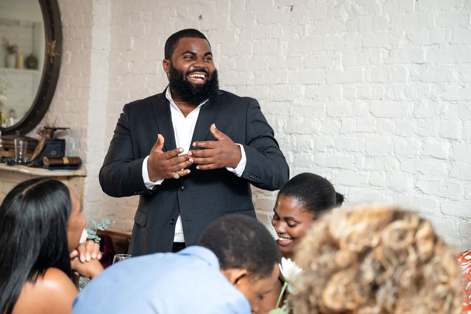 A speaker addresses wedding guests during an indoor celebration.