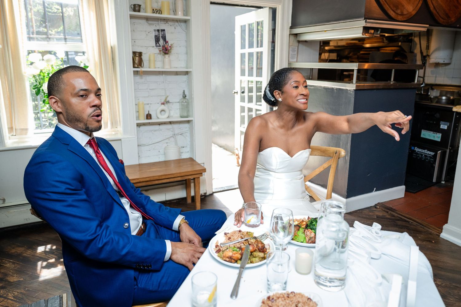 A couple in wedding attire sitting at a dining table during their reception.