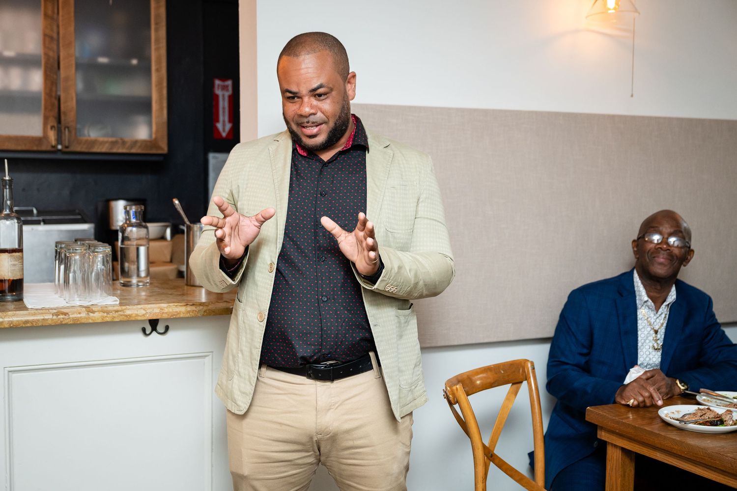 Person in light suit giving a speech during wedding reception.