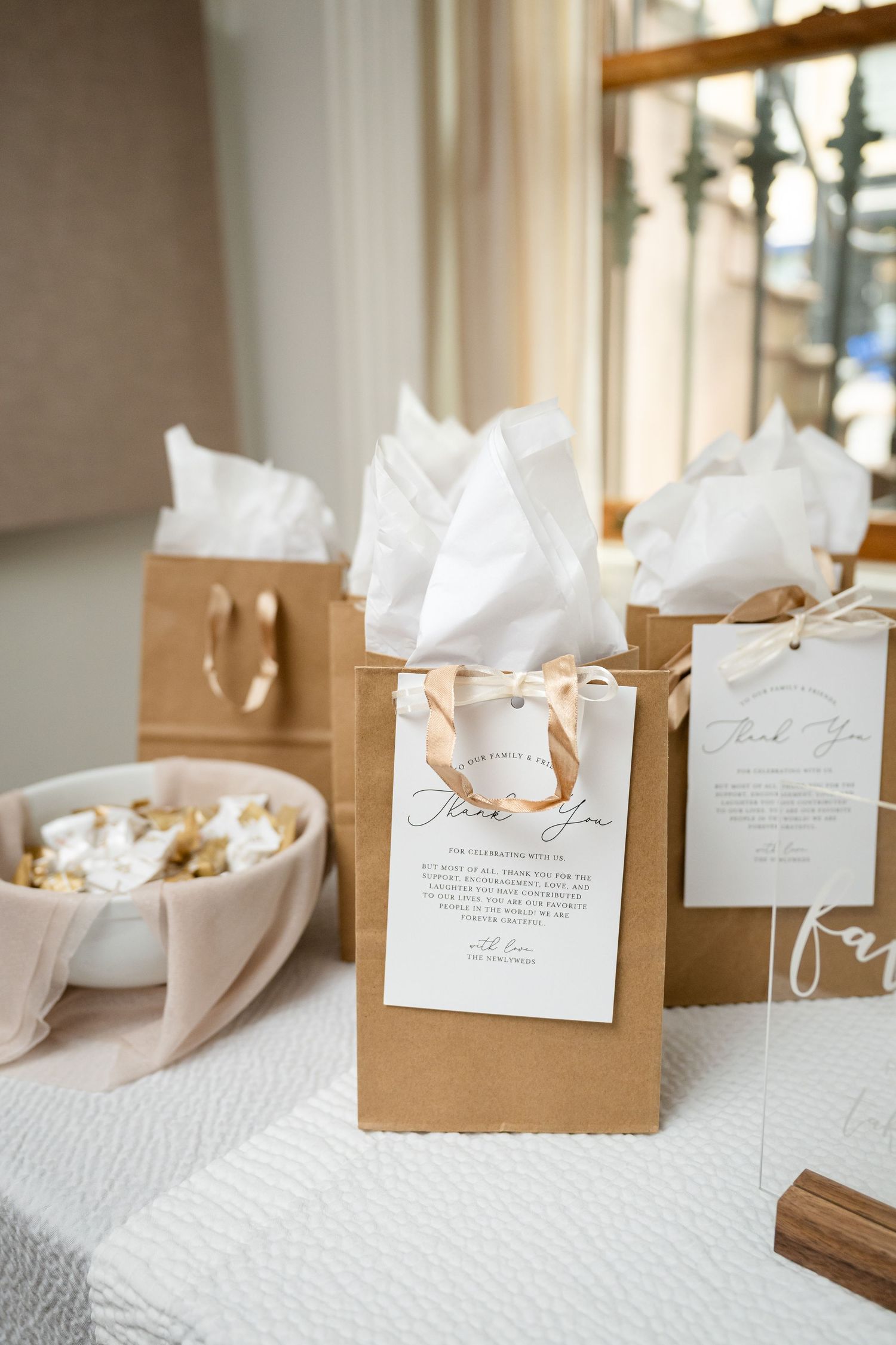 Wedding favor bags with white tissue paper and gift tags on table.