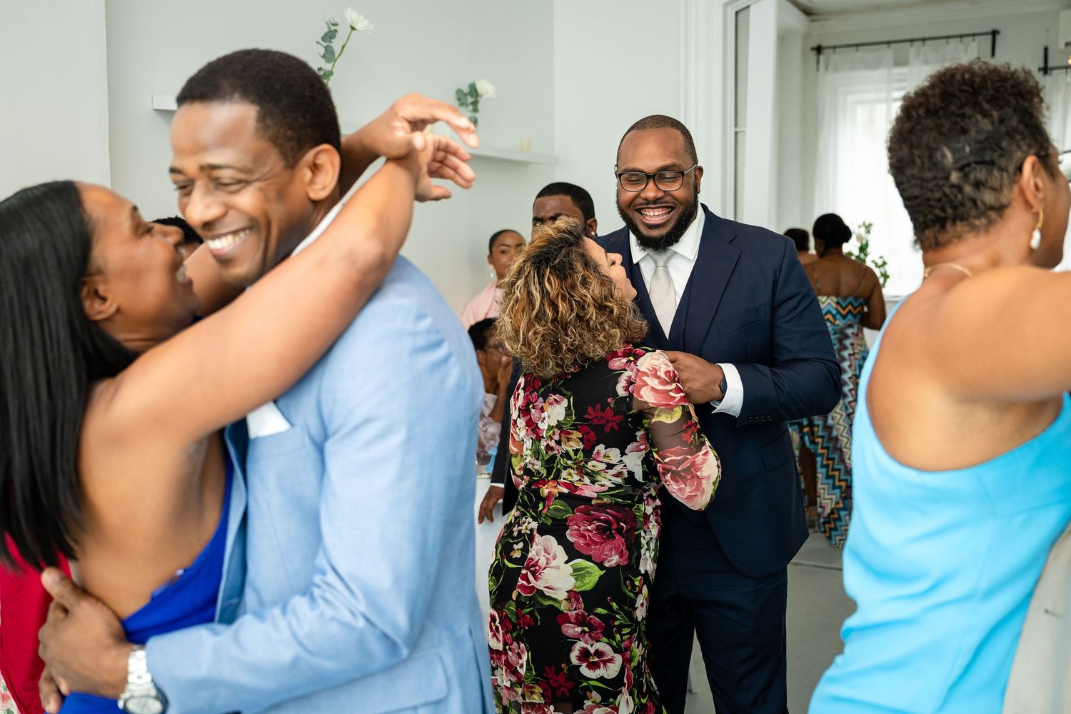 Wedding guests dance and embrace during a joyful reception celebration.