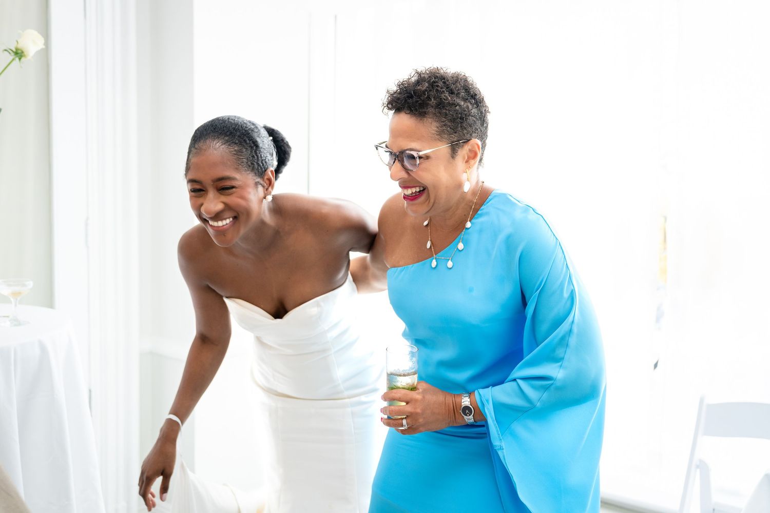 Two people share a joyful moment together while wearing formal attire in a bright interior setting.