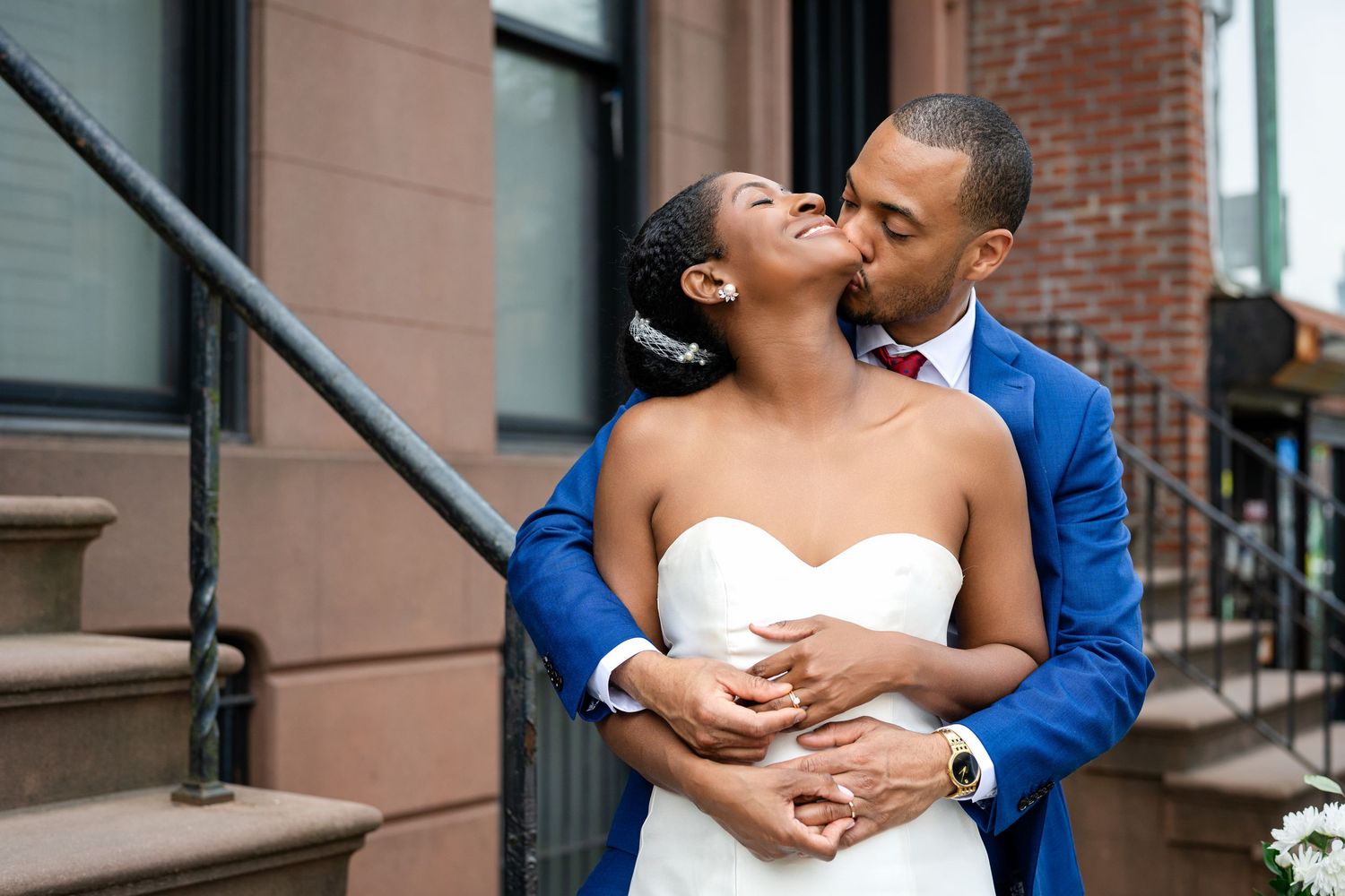 A tender wedding moment shared on brownstone steps in an urban setting.