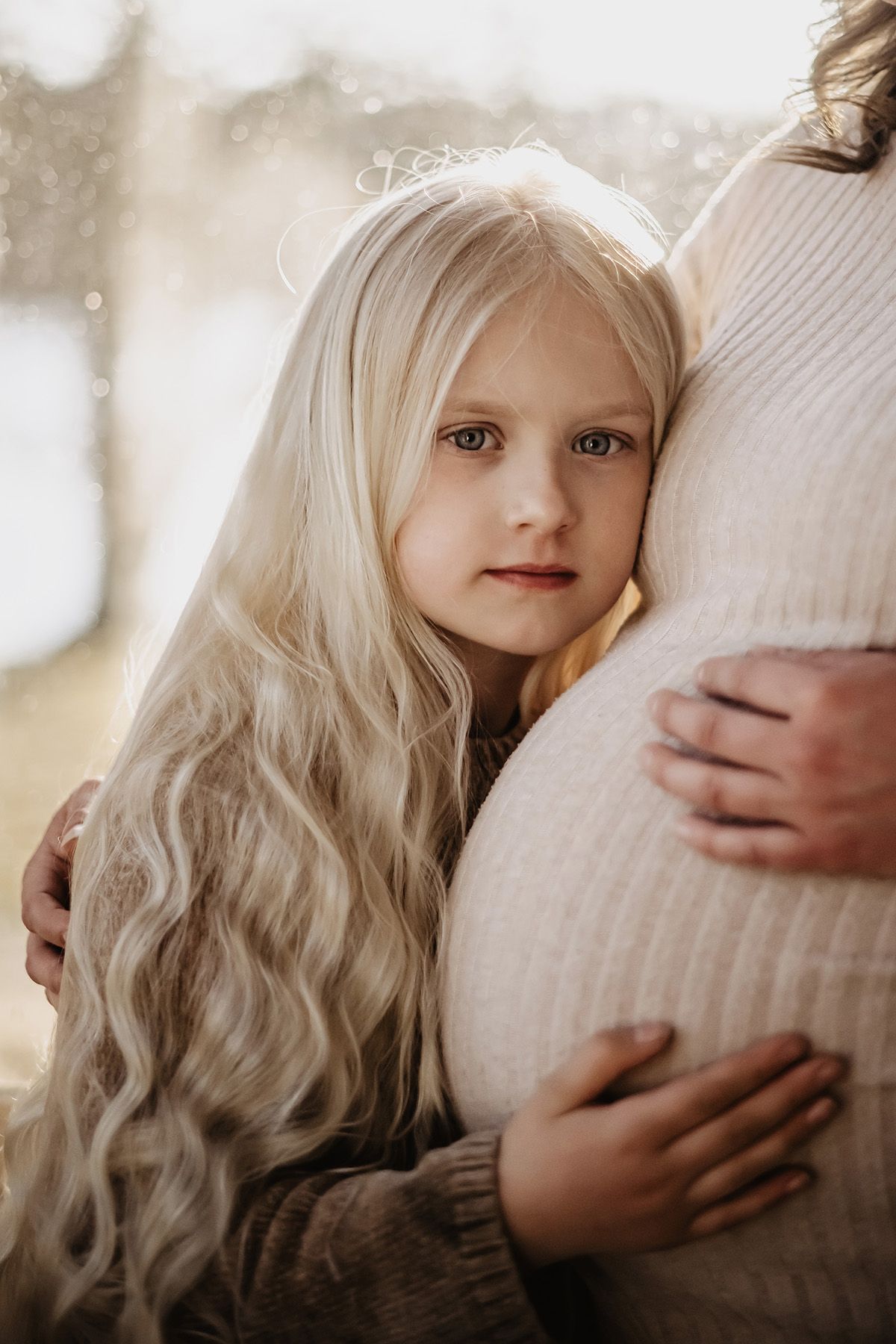 Porträtt på ung flicka i Finspång av fotograf Lets Bloom Media i Östergötland. Flickan lutar sitt huvud mot sin mammas gravidmage.