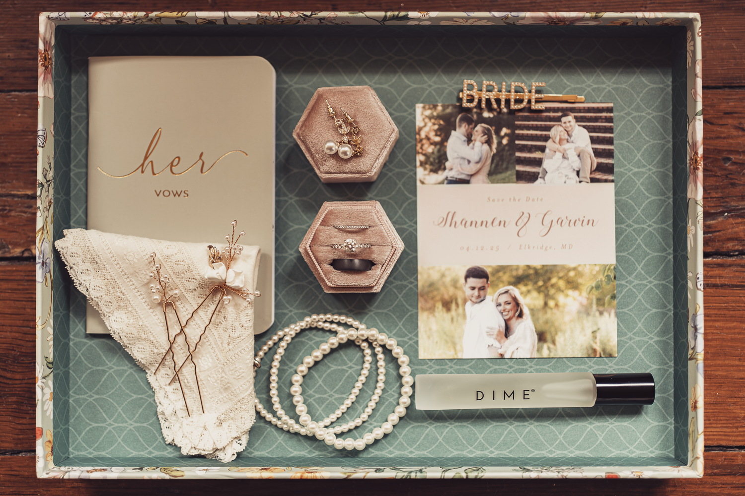 Wedding rings displayed on an ornate gold mirror with a green book and decorative elements on a textured surface.