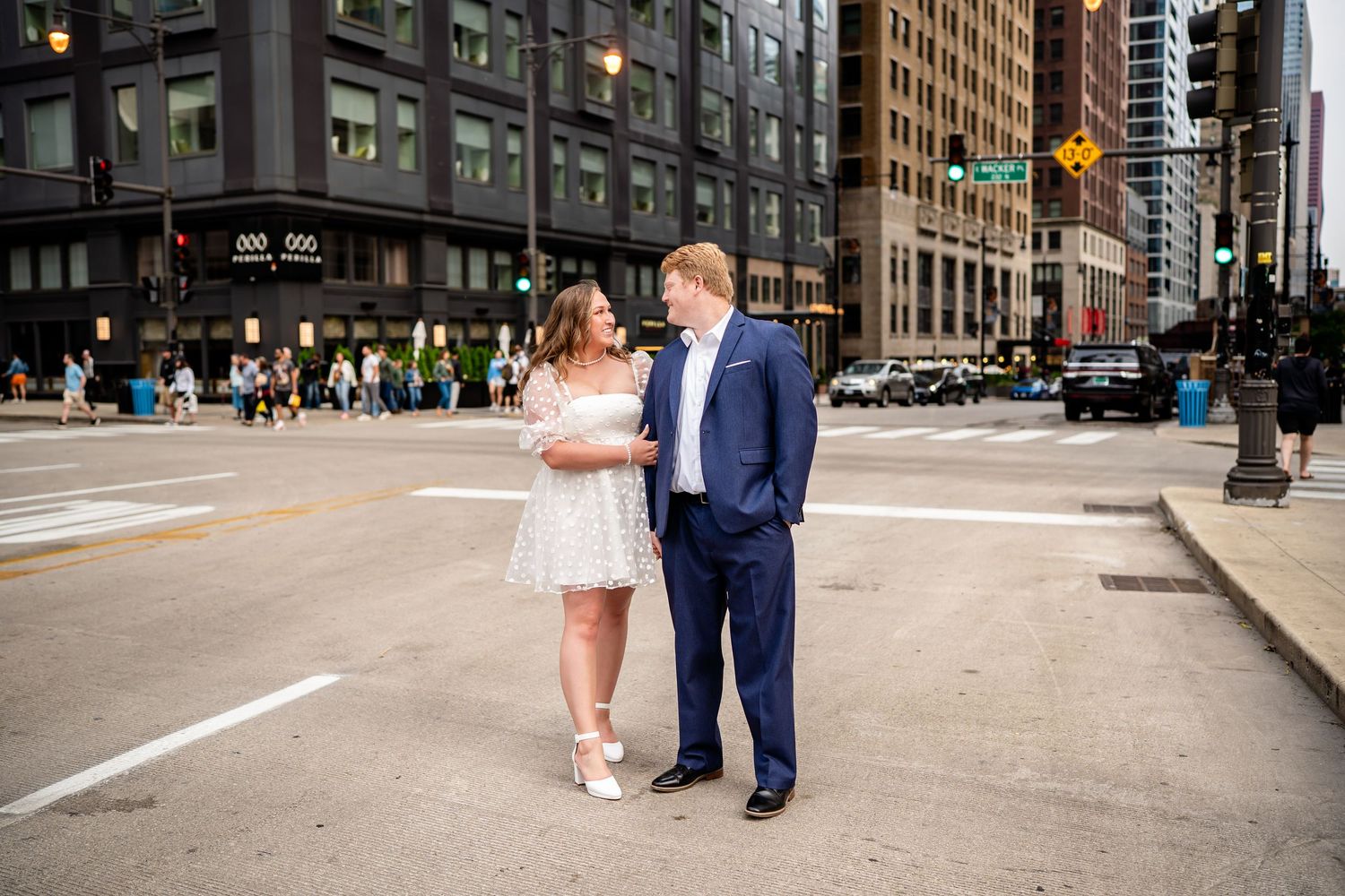 A couple in wedding attire poses on a Chicago street corner with tall buildings in the background.