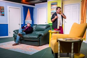 Two figures engage in a dramatic action scene on a couch in a colorfully painted room.