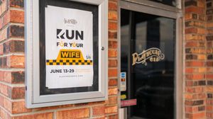 Theater poster for 'Run For Your Wife' displayed in a brick wall frame.