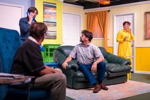 Three performers engage in conversation on a colorfully decorated stage set.