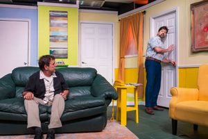 Interior scene showing a dark green leather couch against colorfully painted walls with artwork.