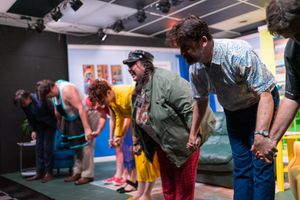 Theater performers lined up on stage during what appears to be a comedy performance or rehearsal.