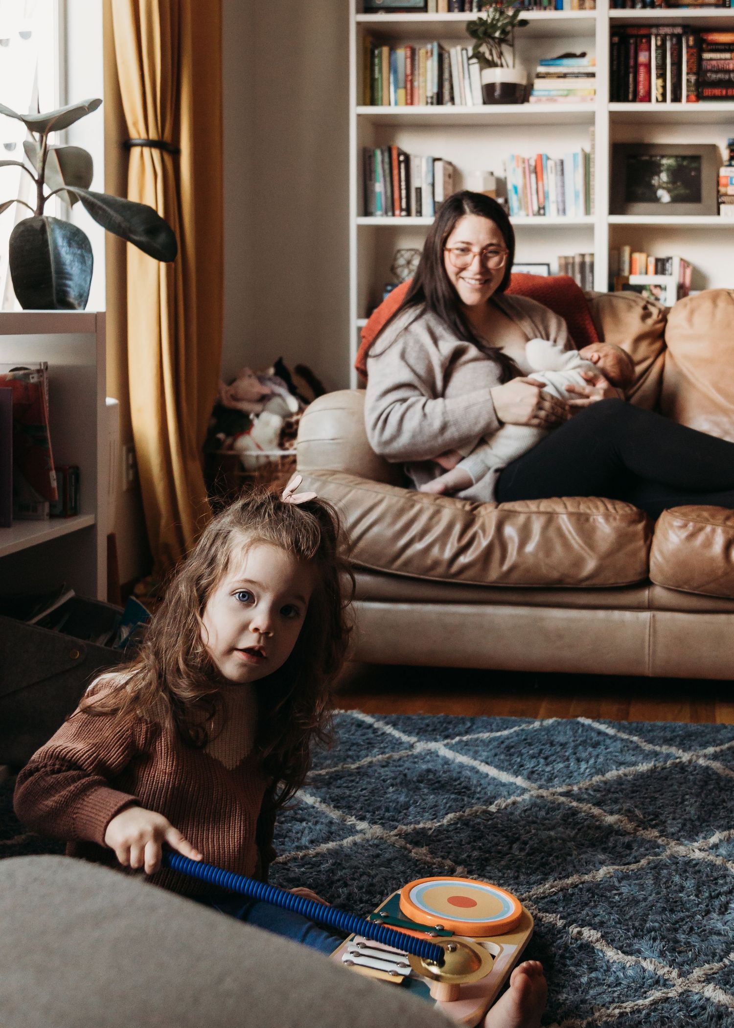 Cozy living room scene with a leather couch, built-in bookshelves, and a geometric patterned rug.