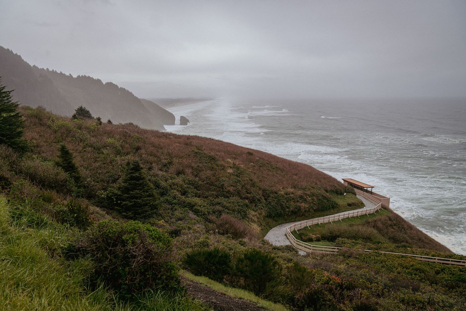 Aerial photo of cloudy Oregon Coast near Sea Lion Caves, showcasing rugged cliffs, ocean waves, and coastal landscape.