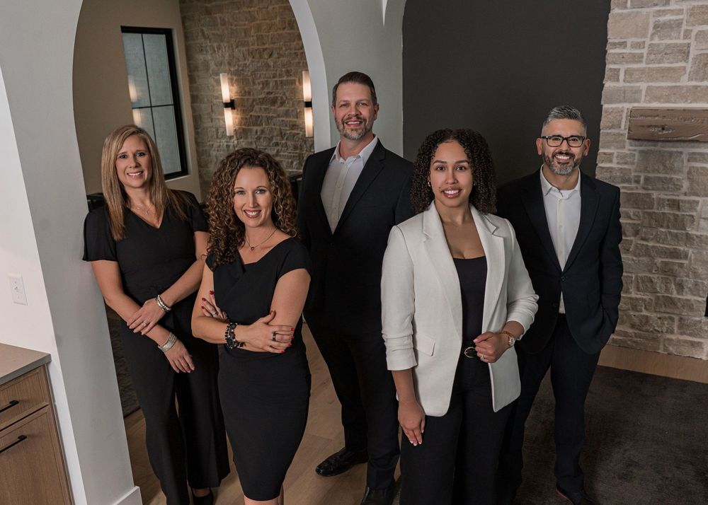 Professional business team standing together in modern office space with brick walls and archways.