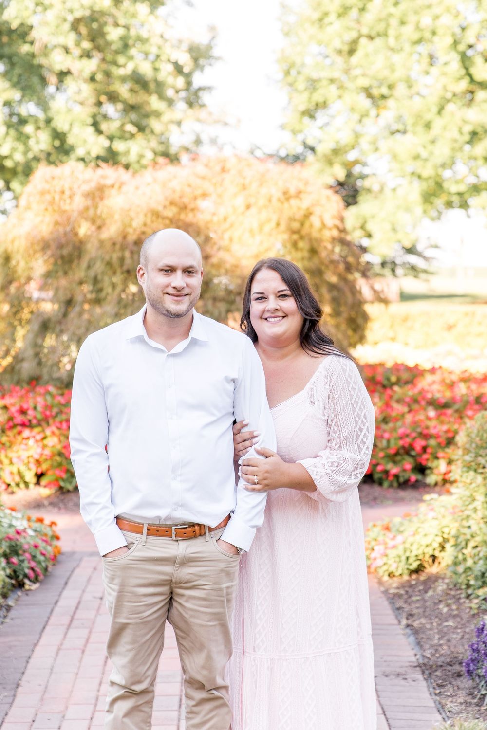 A couple shares joyful laughter together in a beautiful garden setting with autumn flowers and foliage.